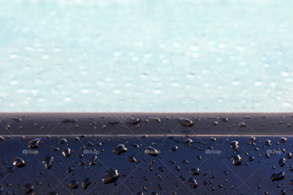 Raindrops on the car side and the car window. Blurred photo background.