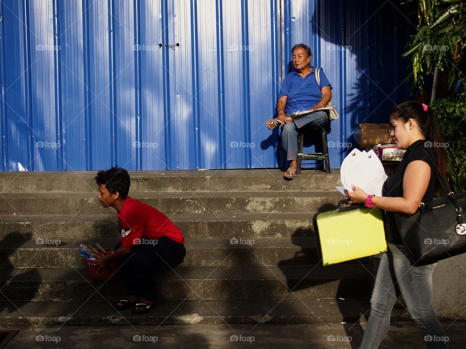 lady sitting against a blue wall and a kid on the steps