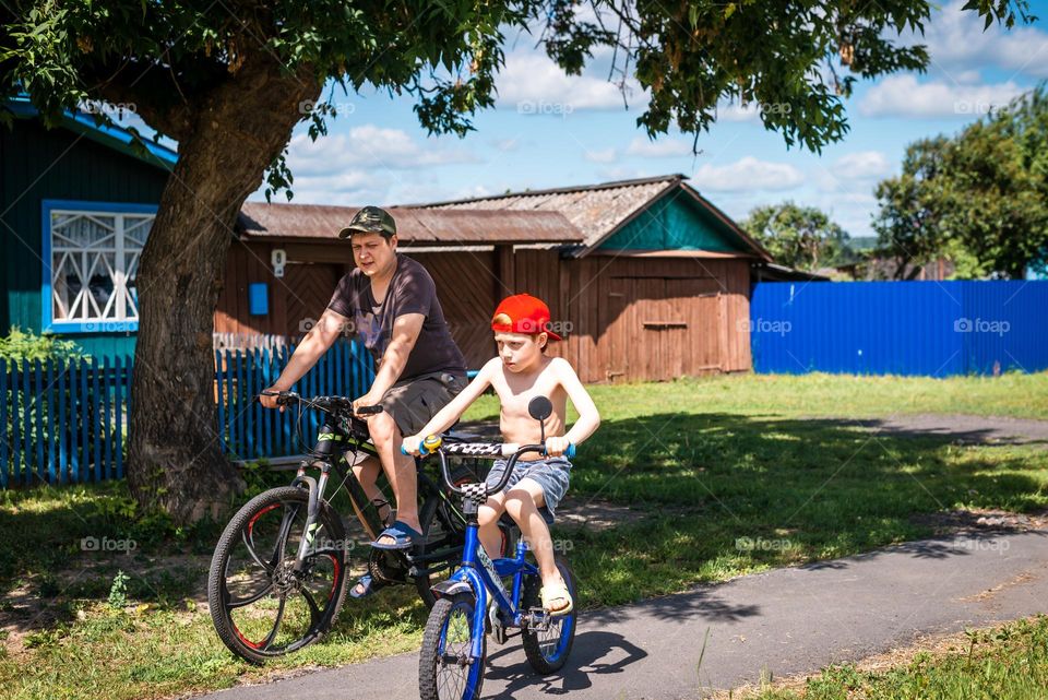 Father and son spend summer in the countryside, ride bikes
