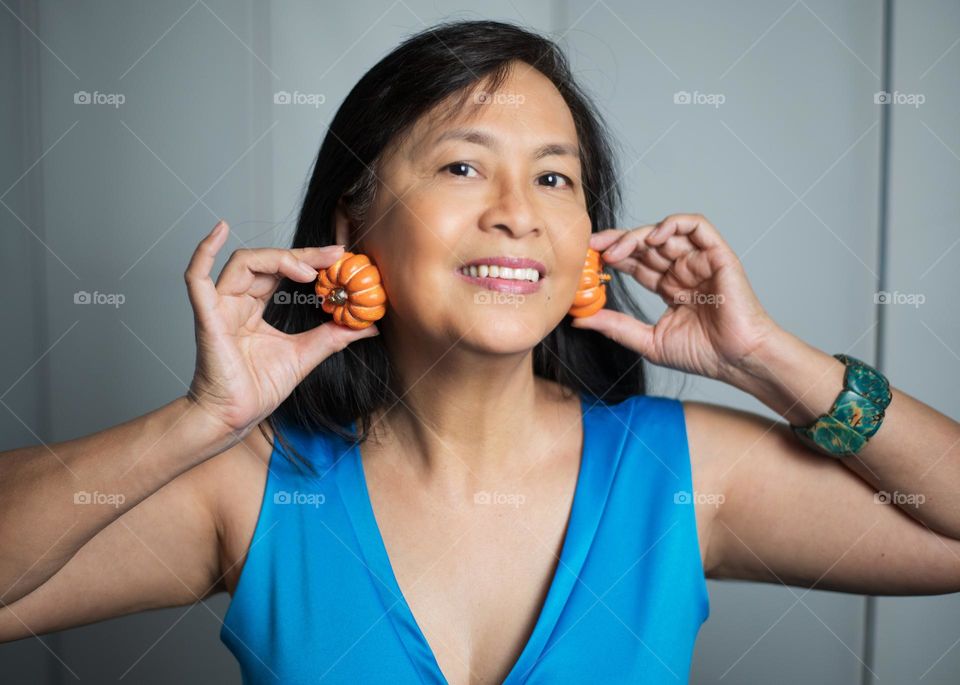 Portrait of a woman holding pumpkin candles on her ears