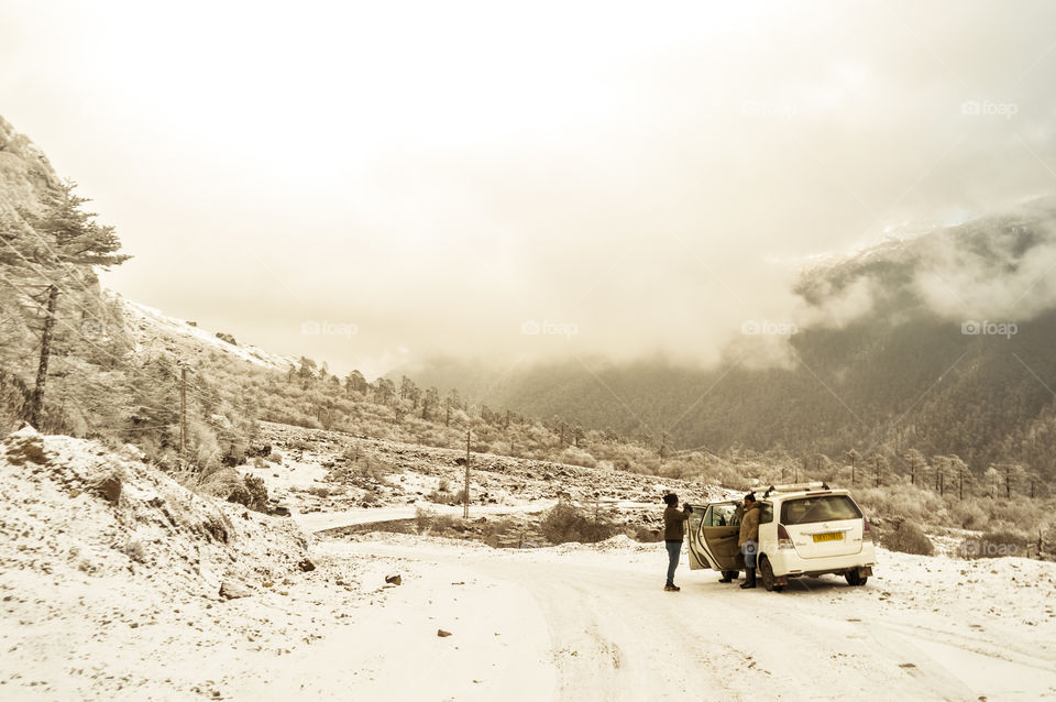 Travelers car halt on a foggy winter road. Indian National highway with a car stopping by at the roadside which is very dangerous due Incessant snowfall in Leh,India