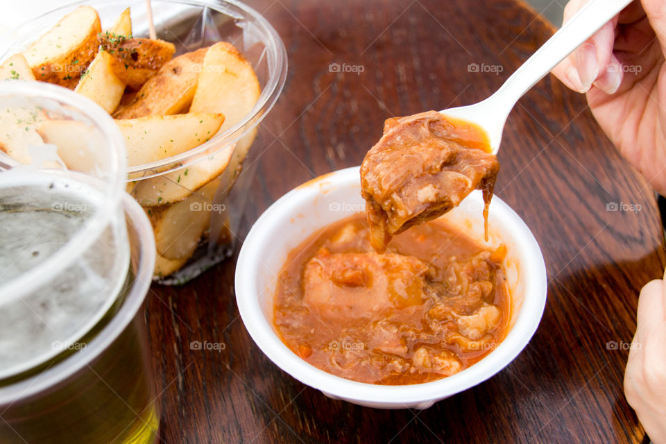 woman eating beef stew at street