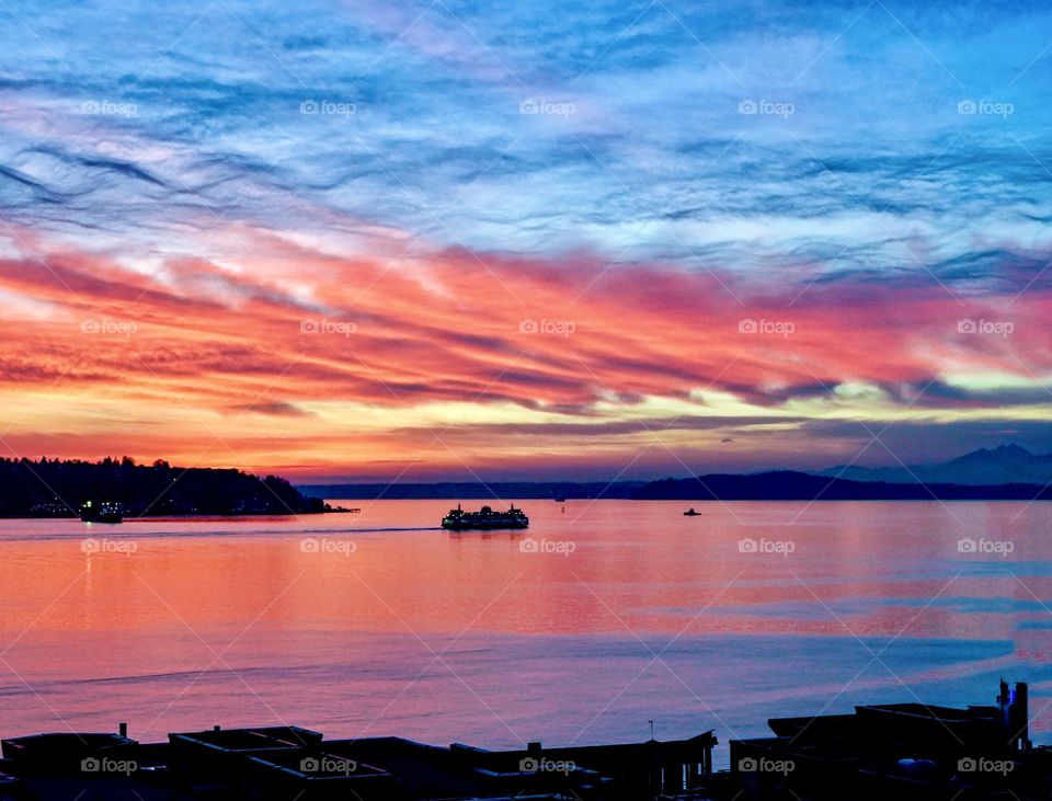 Sunset over ocean with cruise ship and mountains in backdrop 