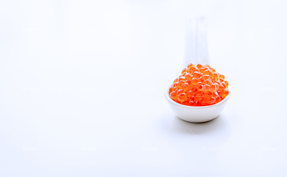 Red salmon caviar in a white dish on a neutral background. Copy space.