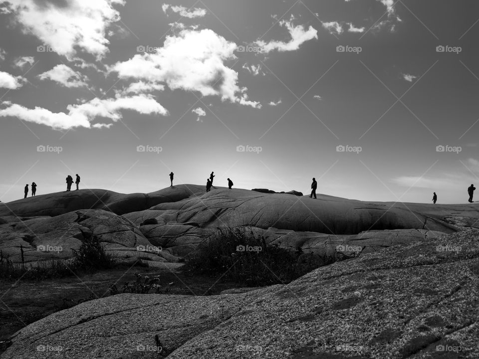 Silhouettes of people walking on a rocky hill