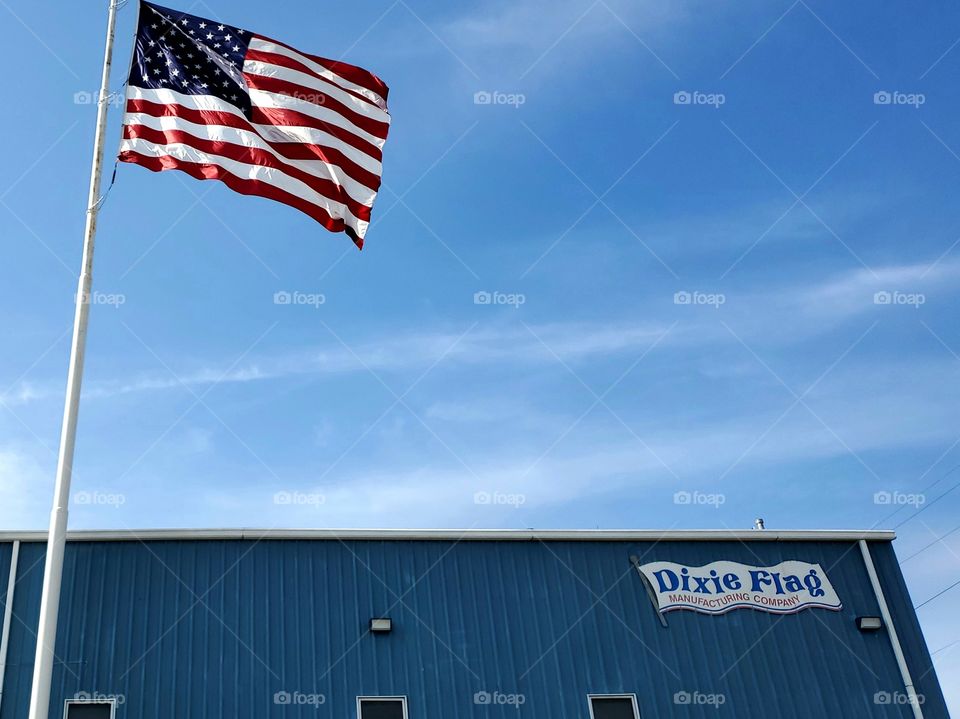 Established originally in 1958 the Dixie flag company flying a large American flag on a bright and sunny blue sky day.  This company has manufactured the flags for many recognized events and places, including four presidential inaugurations.