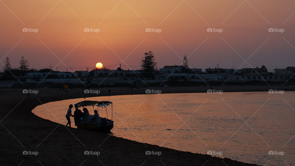 Sunset over the lagoon in Oualidia. The dawn draws its shadows over a fisher's boat