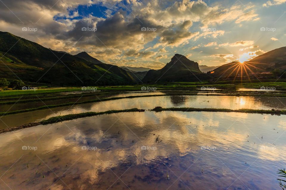 Sunrise in Lim Mong rice valley in water season with dramatic sky and reflection of clouds.