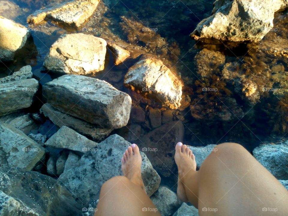 female legs on the stones sea shore texture