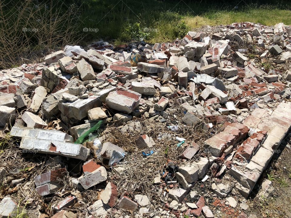 Pile of bricks and rubble outside by the side of the road.