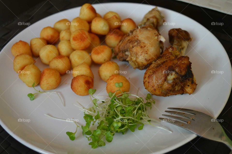 A delicious dish. Chicken legs with baked potato balls and salad from the fresh cress.