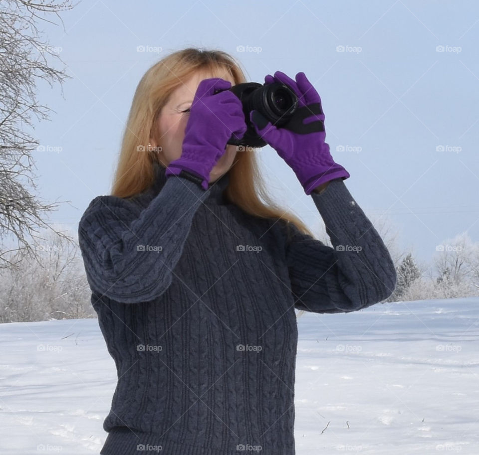 Young Lady taking winter photographs while wearing purple Manzella Gloves 
