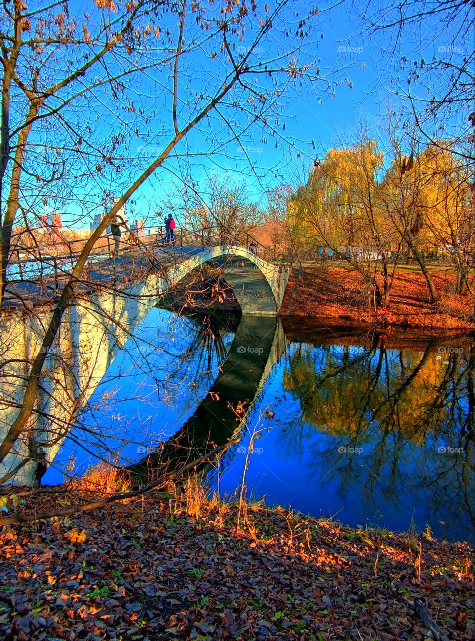 Reflection.  Bridge over the river.  Reflection in the blue water of the bridge and autumn trees