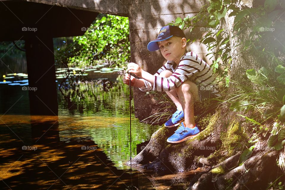 Boy sitting beside a river