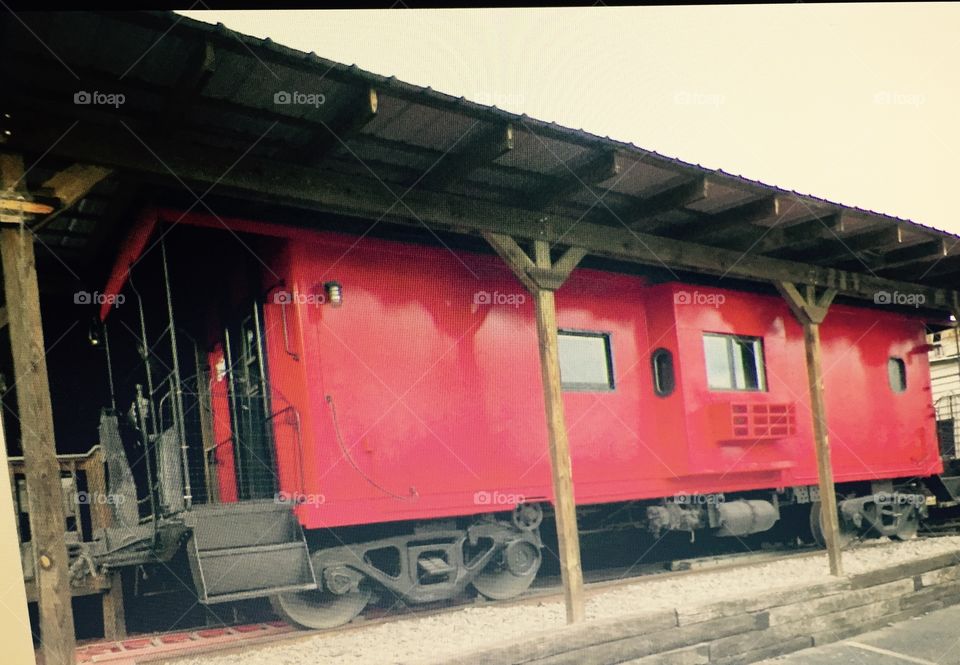 Red caboose under a  erected covering.