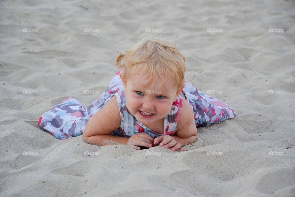 Little cut girl is playing in the sand on a beach of Majorca, Spain.