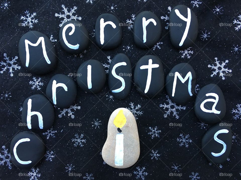 Merry Christmas on black stones over a black carpet 