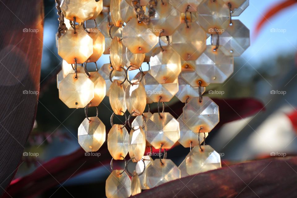 Sparkly octagonal glass beads on a garden wind chime reflecting afternoon sun