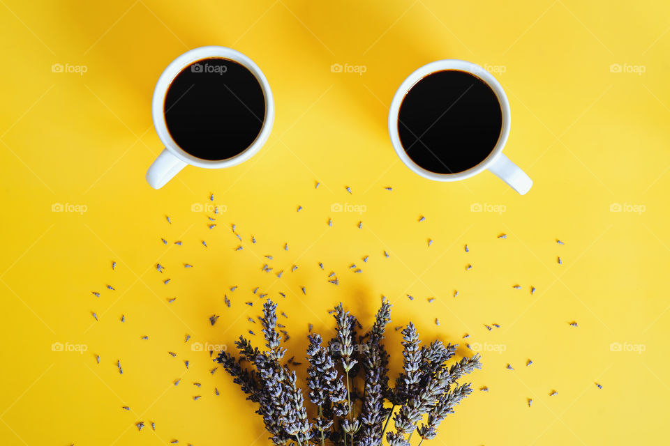 Businessman working morning with cups of coffee and lavender bouquet on yellow background. Flat lay, top view.