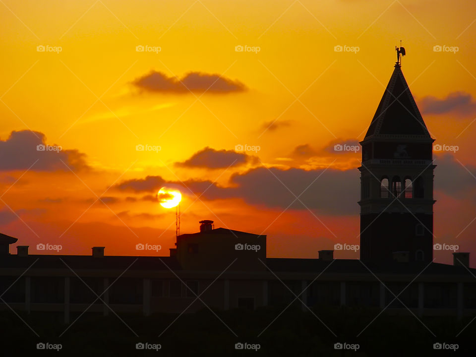 Golden sunset over the mountains and silhouette of a tower