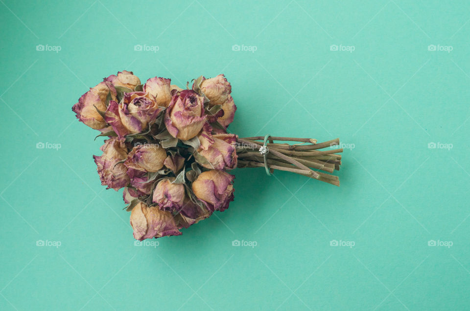 Bouquet of dry flowers and ring on green background 