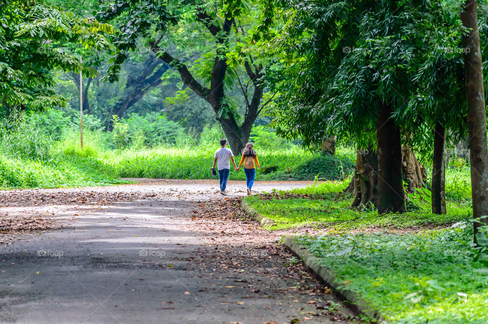 Portrait of two joyful young loving Couple walking in a green autumn park on a romantic summer day. Pre-wedding marriage engagement concept. Togetherness composition. Botanical garden, Kolkata, India