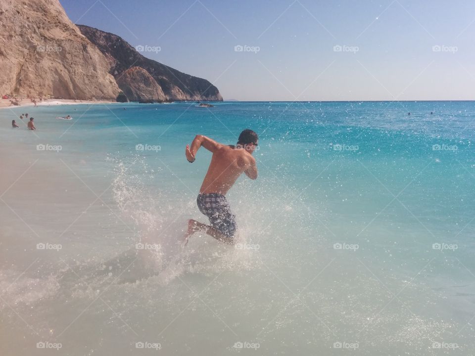 Shirtless man splashing water at beach