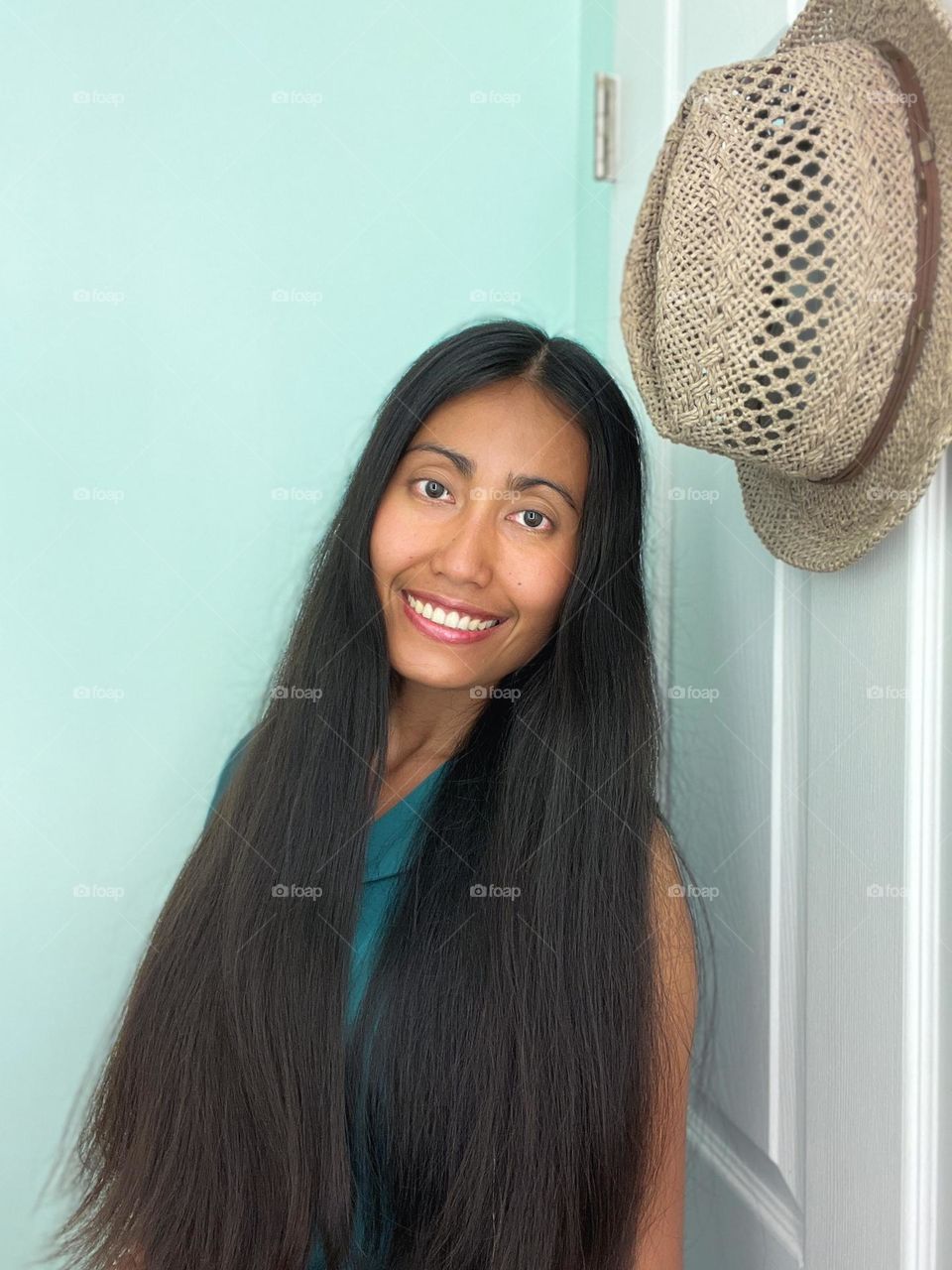  A woman with black long hair and a hat hanging on the white door.