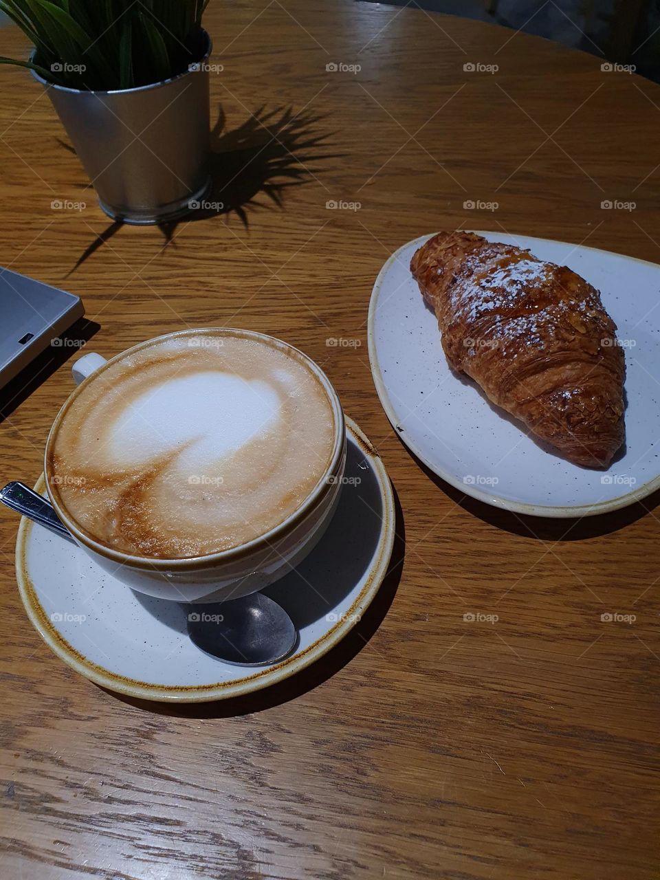 A cup of coffee with a croissant.