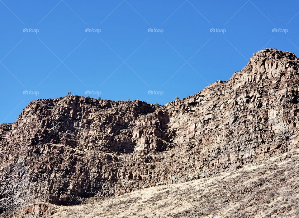 Hills along the Crooked River Highway made from andesite and basalt flows on a sunny fall day with clear blue skies in Central Oregon.