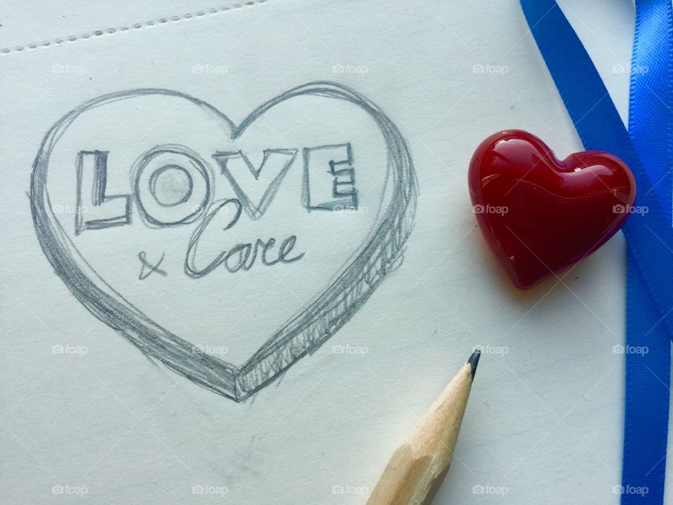 Hand drawn heart, love & care. With pencil and a glass heart and blue ribbon.