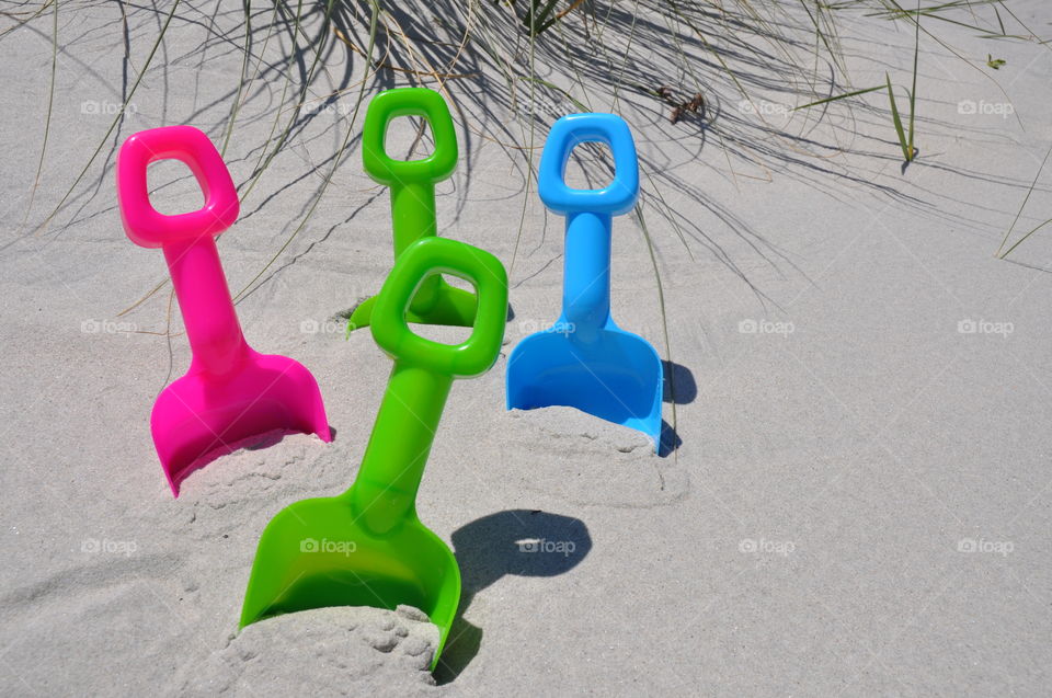 Colorful toy shovels in the sand. 