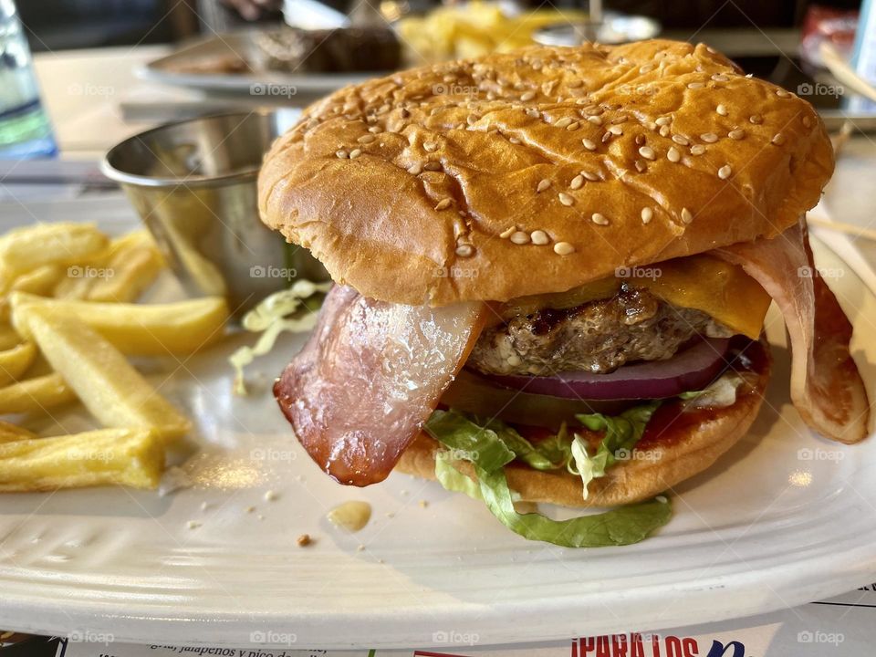 Hamburger with bacon and French fries close up, American style food, fast food, comfort food, sandwiches type, meal with friends, meal break, sesame bun