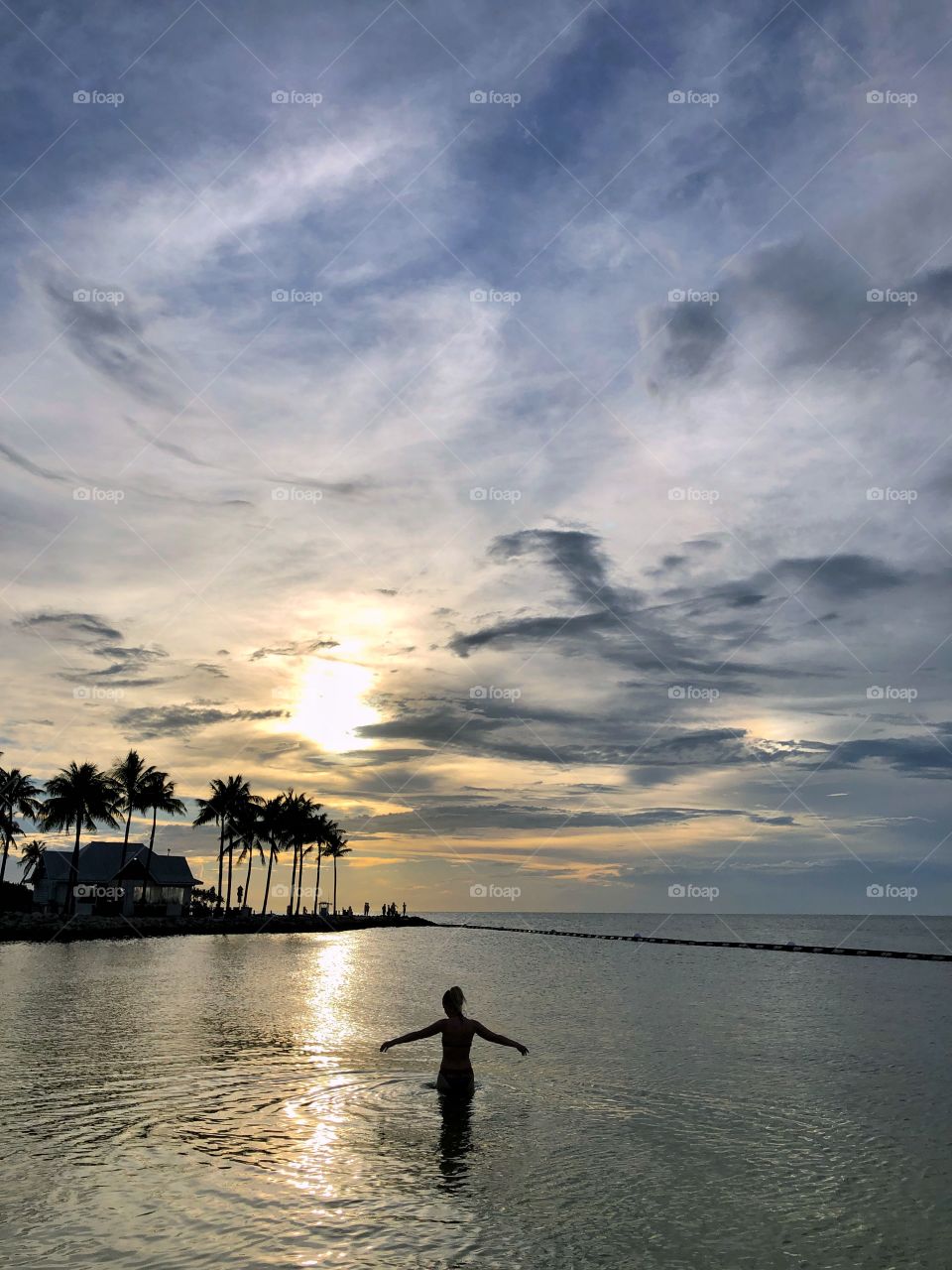 A woman in the ocean on a tropical island in sunset