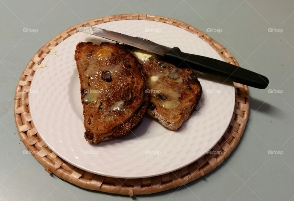 Two slices of toasted fruit loaf  butteted on a plate for breakfast.