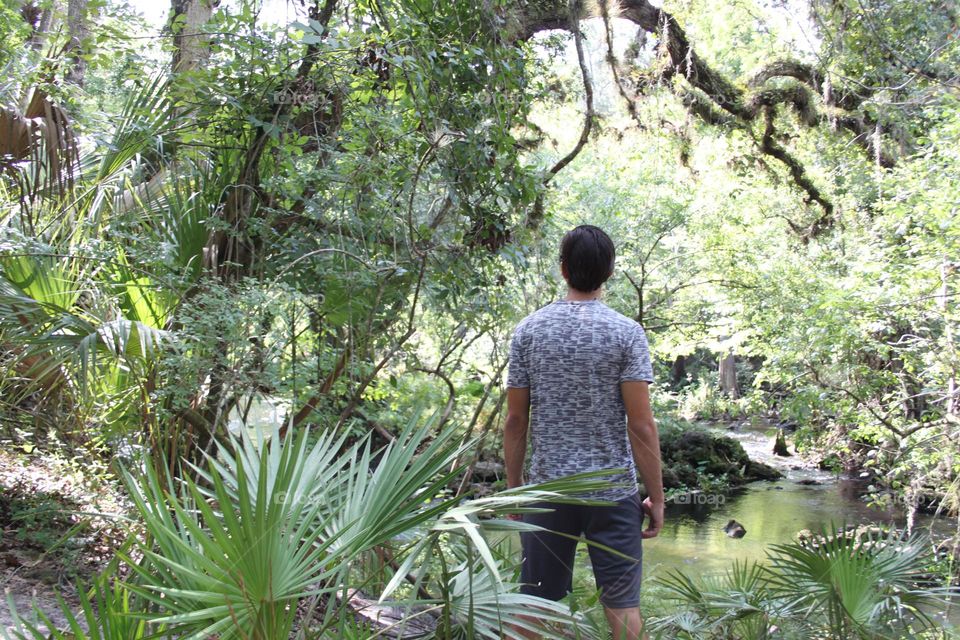 Man in nature pondering life by river’s edge