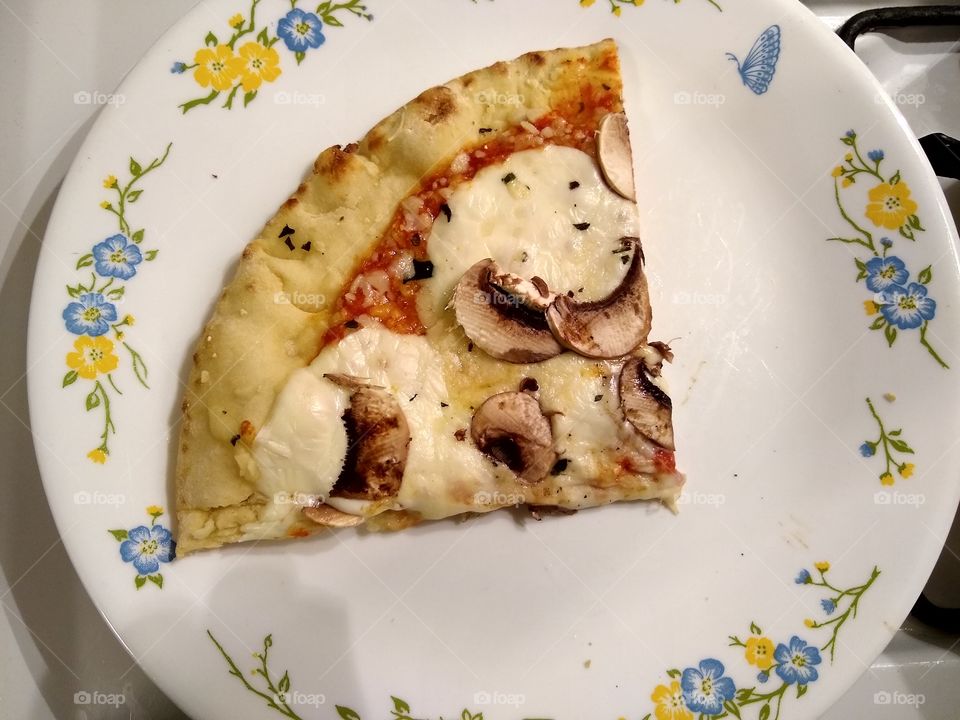 Pizza Margherita with fresh sliced mushrooms on a floral design plate.