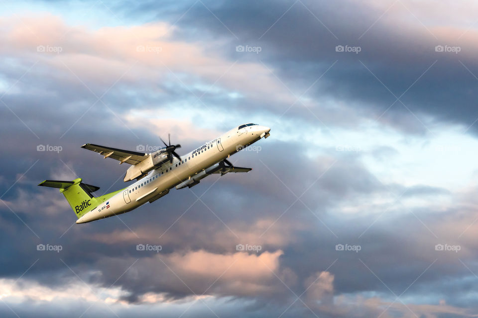 passanger airplane Bombardier DHC-8-400 on a sunset sky background