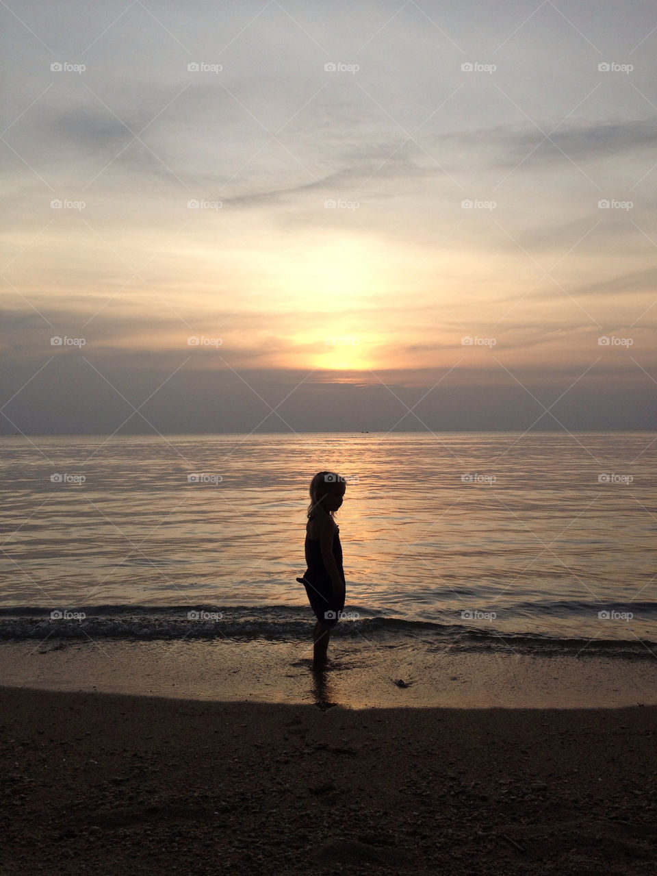 Small girl in backlight on a beach at sundown