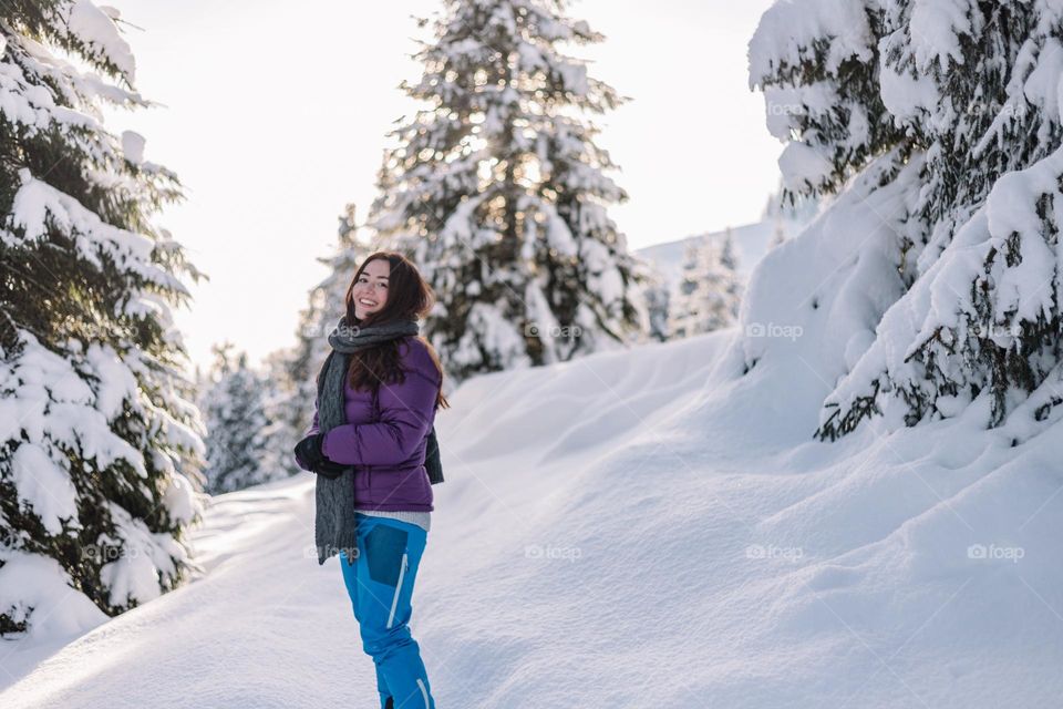 Woman being happy while hiking in winter in an incredible landscape with fresh snow.