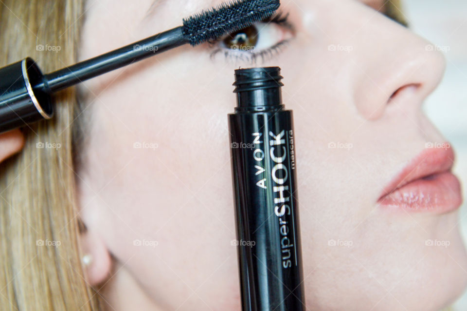 Woman applying AVON Supershock mascara to eyelashes