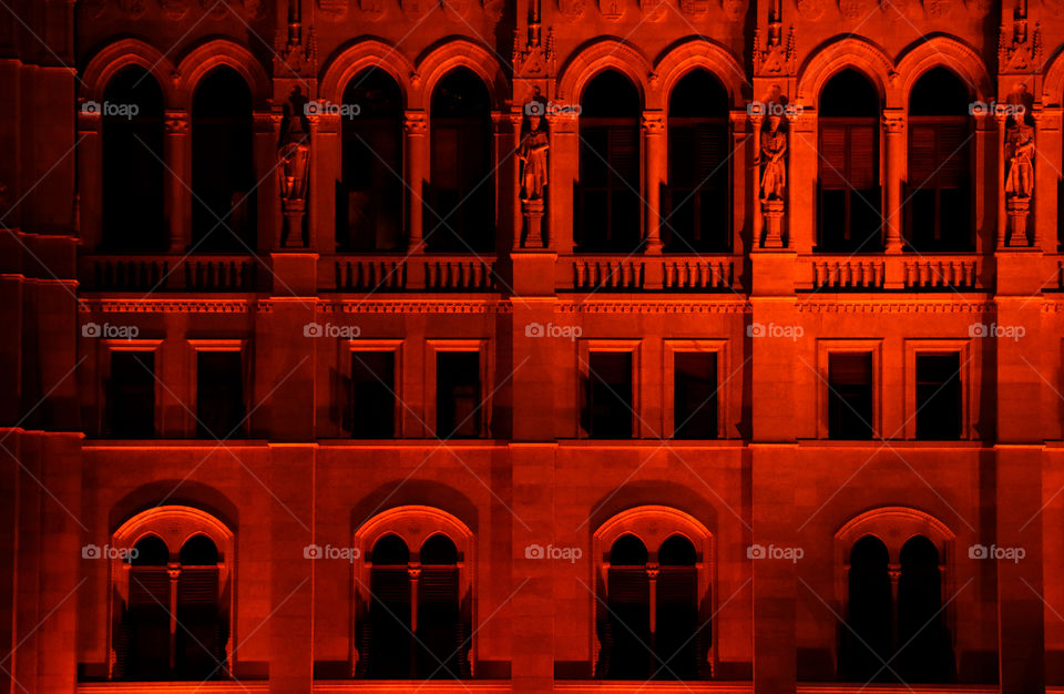 Illuminated red colored façade of the Hungarian Parliament Building in Budapest.