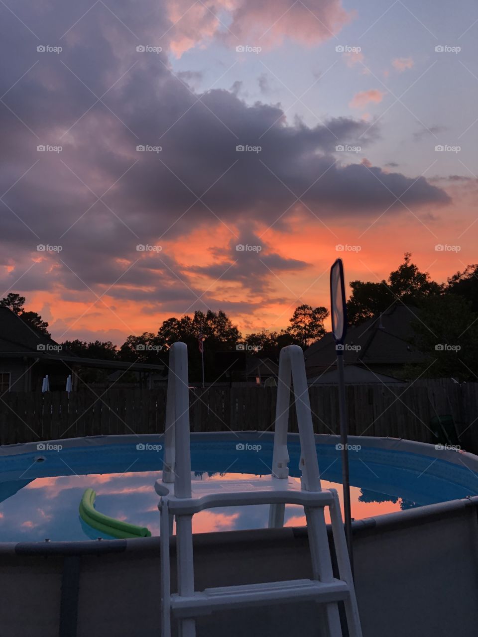 Bright orange purple sunset sky with orange pink reflected on the pool water. 