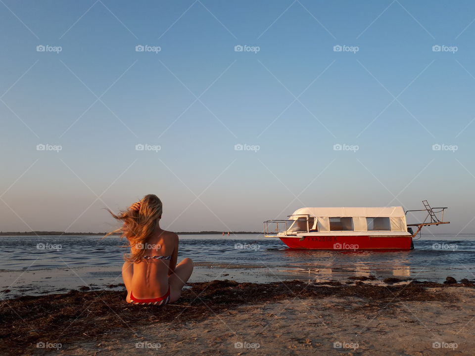 Girl sitting at the beach near boat