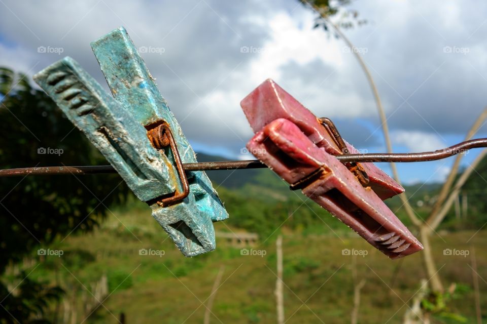 Two aged clothespin as friends on a clothes line
. 
Two old and weary clothespin as friends on an outdoors clothes line in a tropical setting in Manicaragua, Cuba on Christmas eve 2013. 