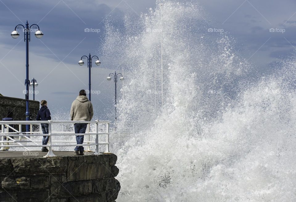 A father and so match the huge waves crash against the key side