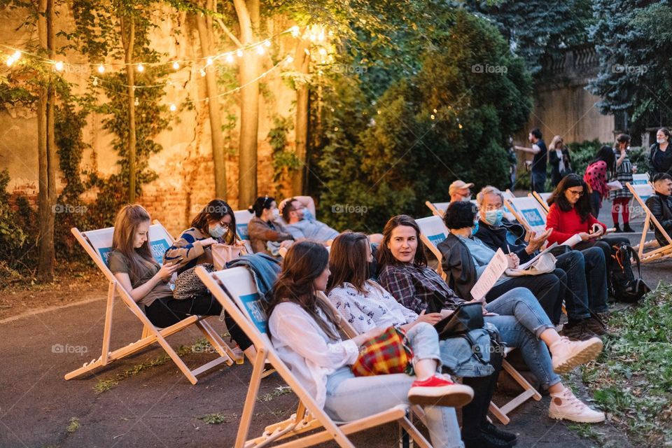 People talking while waiting for the movie to start, while being in a public space in the city.