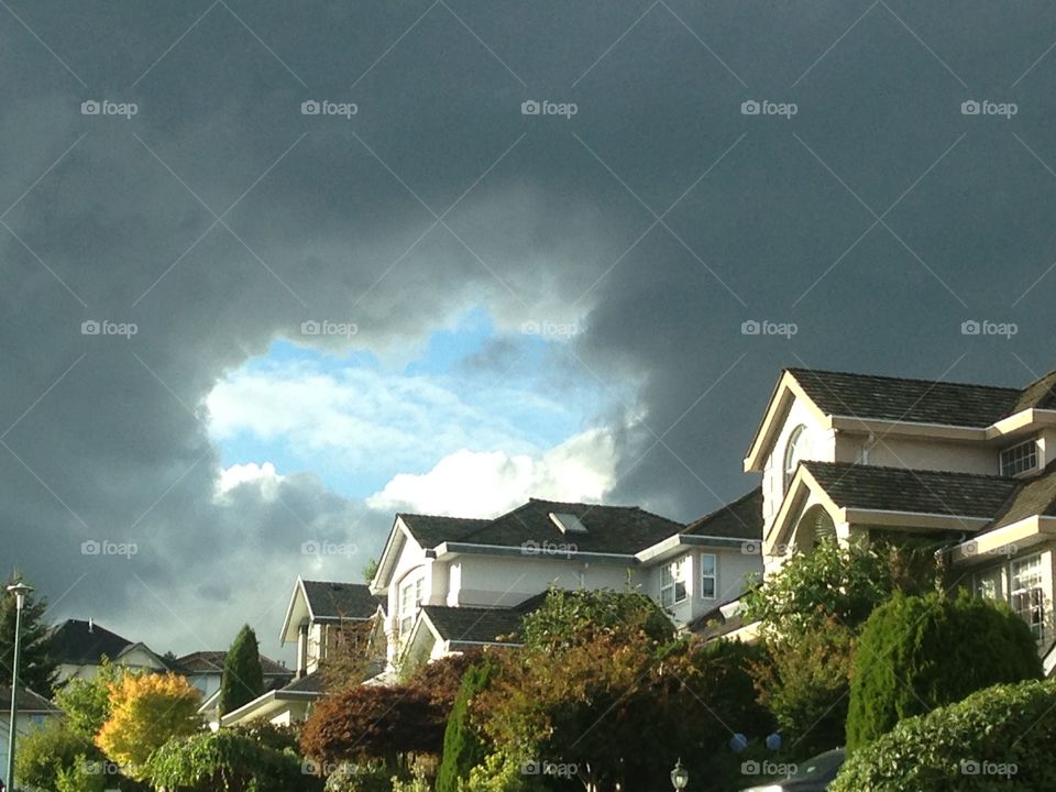 Mortgage boom or bust?. Blue portal through dark clouds over homes on hill