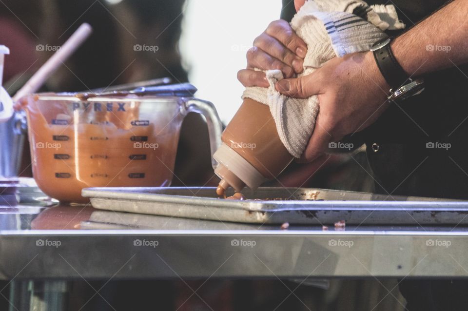 Chef using squeeze bottle of caramel to make candy 