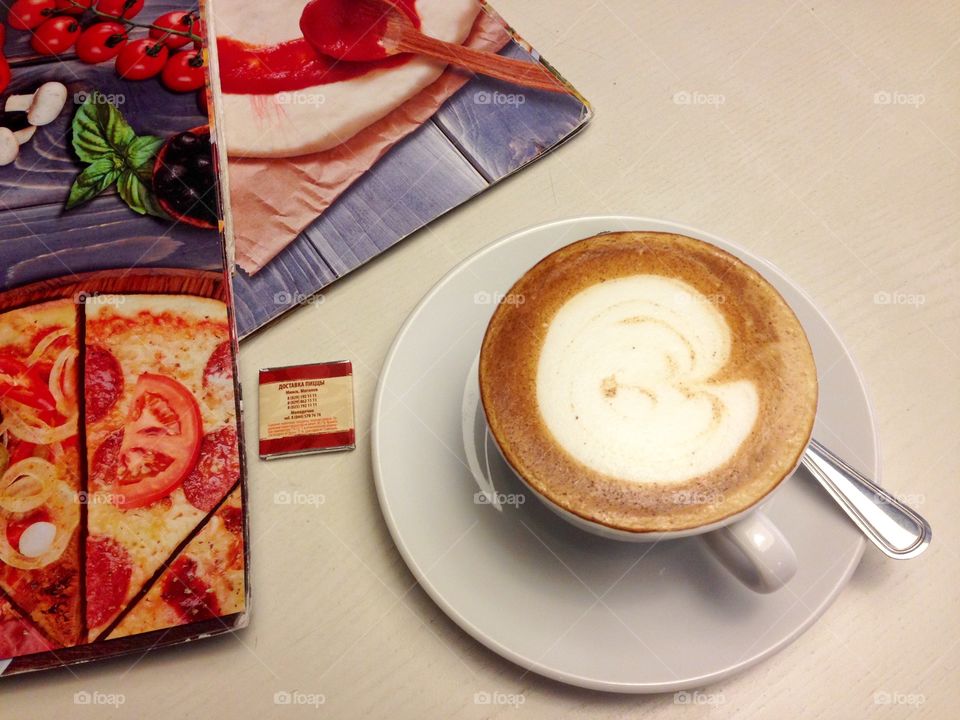 Cap of hot cappuccino and menu on the table 